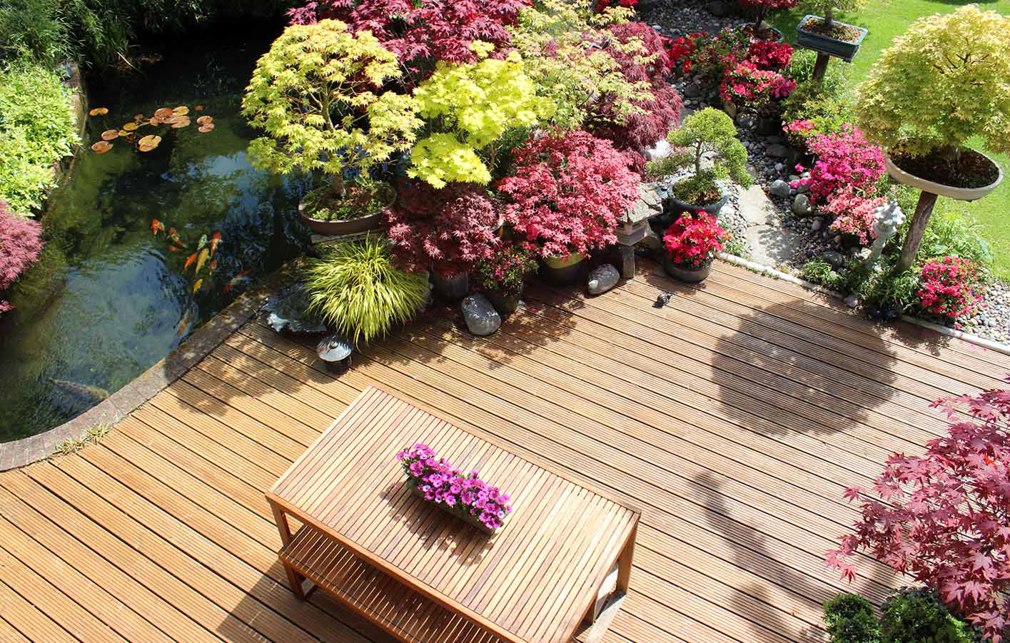 Holzterrasse im Garten umgeben von bunten Blumen