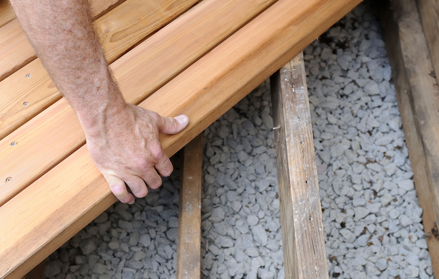 Hand die eine Terrassendiele aus Holz verlegt